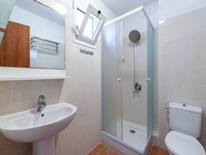 Ein Badezimmer mit Duschkabine, Waschbecken, Toilette und Spiegel.