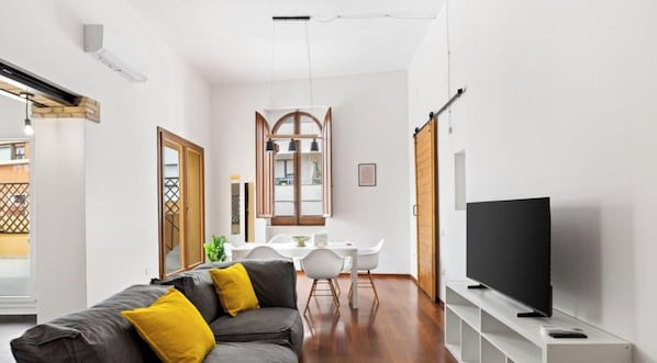 A modern living room with a sofa, a dining table, and a TV. - Billy's House – Spacious comfort in the heart of Cagliari 🌿✨ (Cagliari)