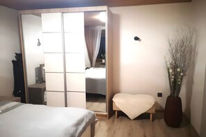 A bedroom with a bed, a bedside table, a chair, a wardrobe, and a vase with dried flowers. - Ideal Base for Excursions and Hikes, 70 sqm, Step-Free Access, Parking at the Apartment (Issigau)