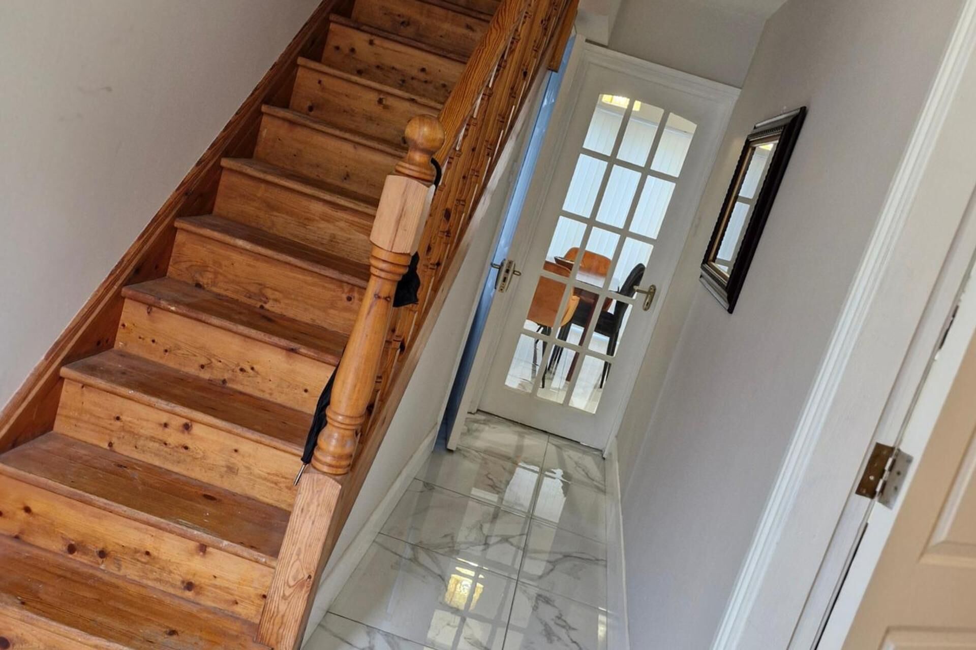A wooden staircase with a handrail leading to a door with a glass panel.