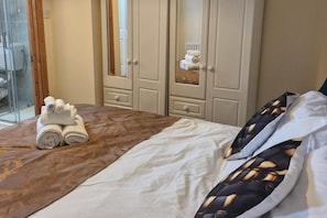 Une chambre d’hôtel comprenant un lit, un ensemble d’armoires en bois et une cabine de douche en verre.