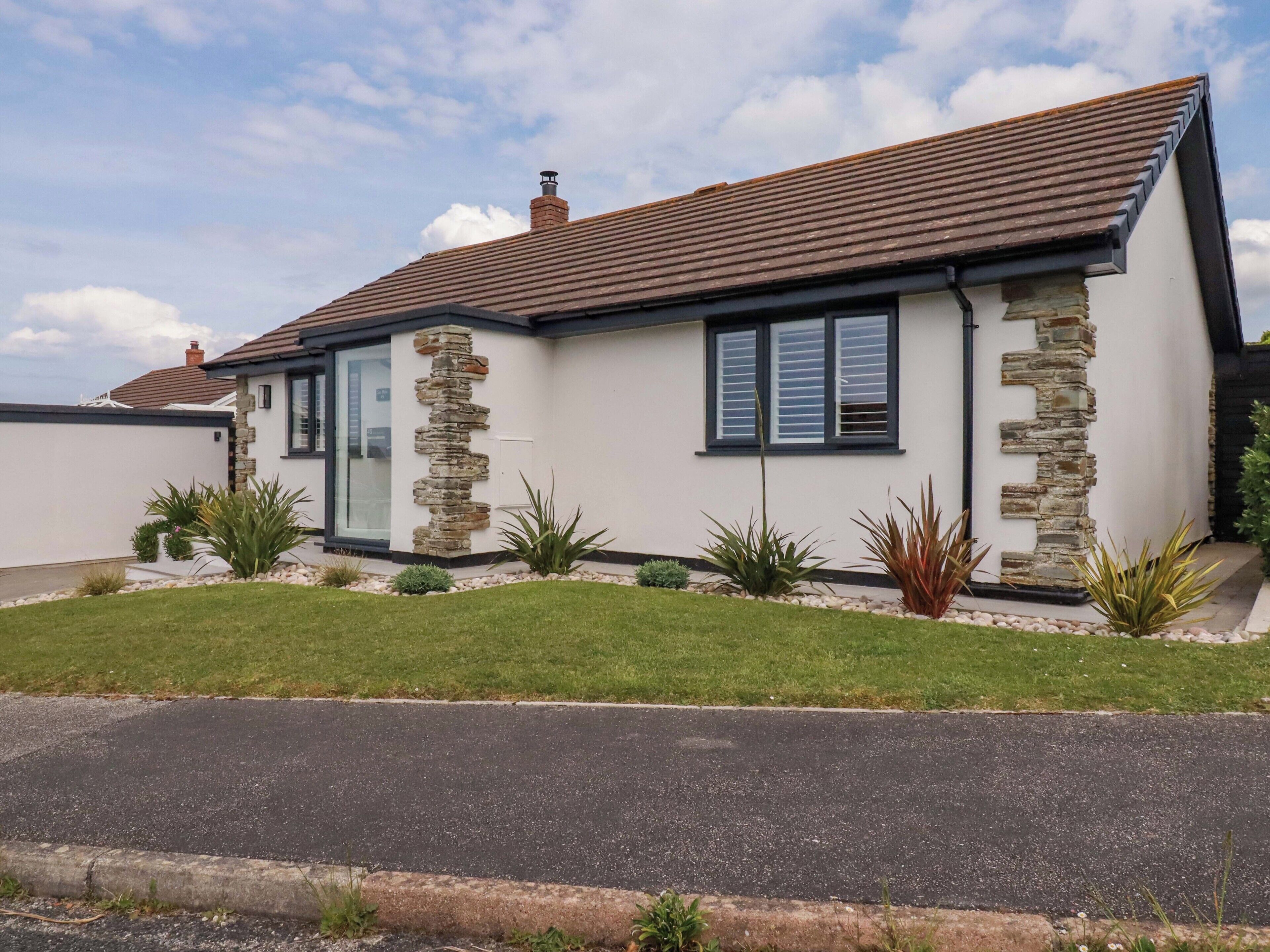 A modern house with a stone facade, a sloped roof, and a well-maintained lawn.