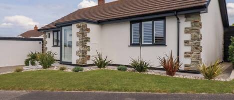 A modern house with a stone facade, a sloped roof, and a well-maintained lawn.