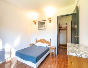 Ein Schlafzimmer mit einem hölzernen Bett, Nachttischen, einer Wandlampe, einem gerahmten Bild und einem Kleiderschrank.