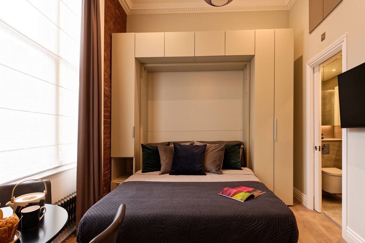 A neatly arranged bedroom with a bed, bedside table, and a television.