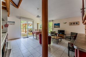 Amplia sala de estar con cocina, comedor y un ventanal con vistas al exterior.