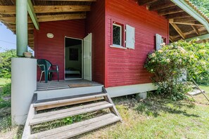 A red wooden house with a porch, a door, and a window.