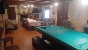 Un salon chaleureux avec une table de billard, une cheminée, une table à manger et un téléviseur.
