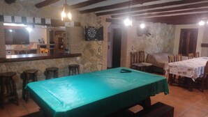 Une pièce avec une table de billard, un coin bar et des murs en pierre.