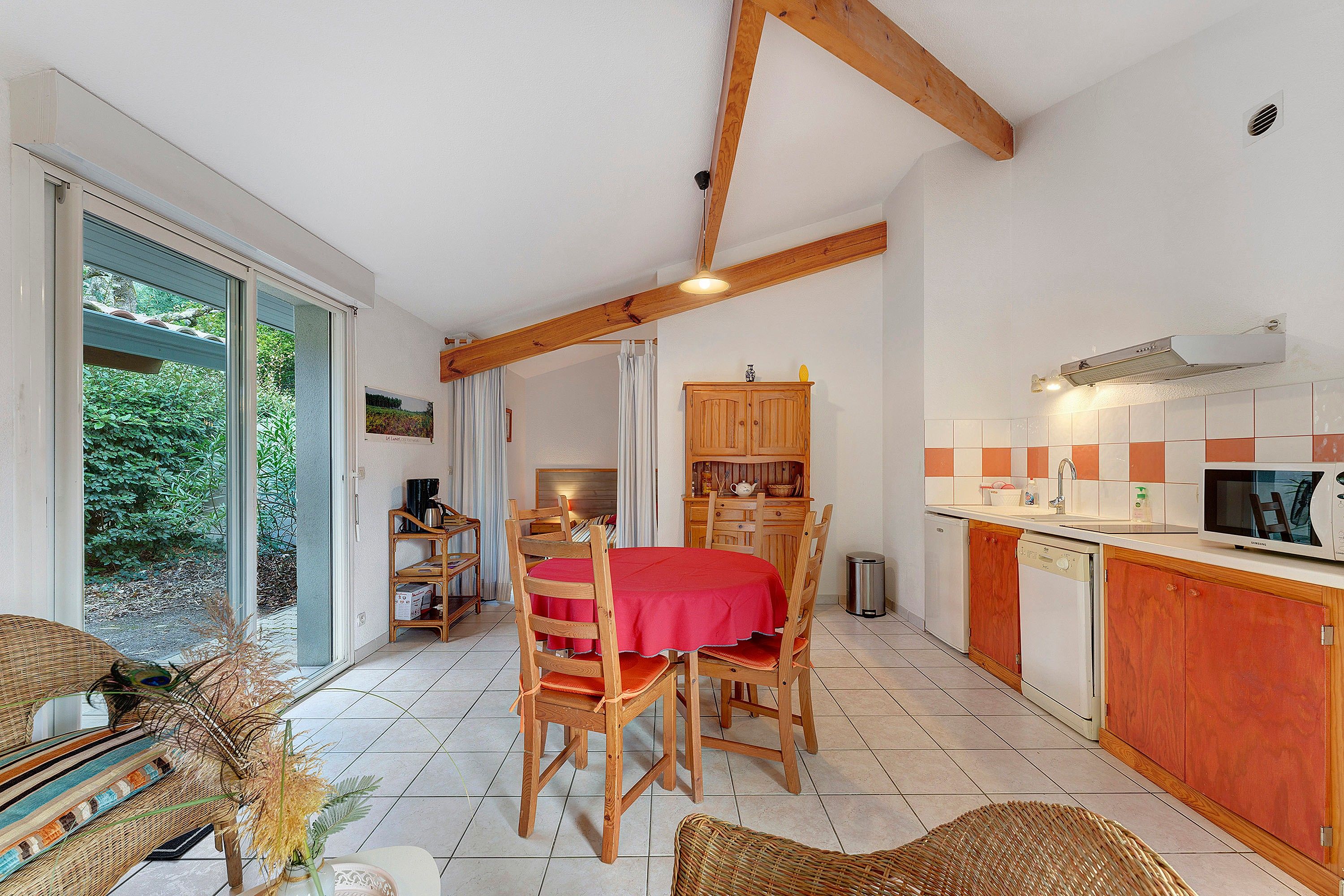 Cocina compacta con comedor, muebles de madera y vistas a través de un ventanal.