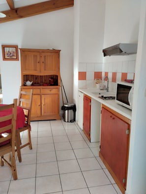 A kitchen with wooden cabinets, a tiled floor, a microwave, and a sink. - “4p Sanguinet - Addax” Apartment with Private Terrace and Wi-Fi (Sanguinet)
