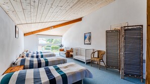 A room with two beds, a crib, a chair, a radiator, and a window. - Apartment "Chott" for 6 in Sanguinet with Terrace (Sanguinet)