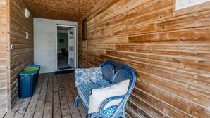 A wooden interior with a wicker chair, a trash bin, and a door leading to another room. - Apartment "Chott" for 6 in Sanguinet with Terrace (Sanguinet)
