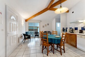 A dining area with a table set for four, wooden chairs, a ceiling fan, and a kitchen area with a microwave and coffee maker. - Apartment '4p Sanguinet-Doum Doum' with Outdoor Space (Sanguinet)