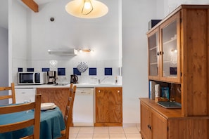 A compact kitchen with a microwave, coffee maker, and a dishwasher. There is a dining table with chairs and a wooden cabinet with glass doors. - Apartment '4p Sanguinet-Doum Doum' with Outdoor Space (Sanguinet)