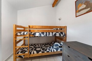 A bunk bed with a checkered mattress and wooden frame in a room with white walls and a tiled floor. - Apartment '4p Sanguinet-Doum Doum' with Outdoor Space (Sanguinet)