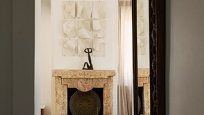 A hallway with a fireplace, a mirror, and a herringbone floor. - Penthouse Under Acropolis (Athens)