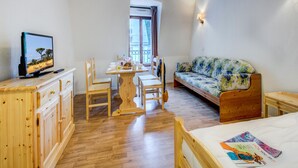 Una stanza con un tavolo da pranzo in legno, sedie, una televisione, un divano e un letto.
