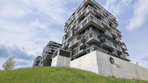 Um edifício residencial alto com várias varandas, base de concreto e céu claro.