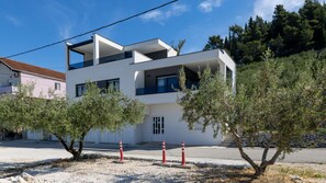 A modern two-story building with balconies, surrounded by olive trees and a clear sky. - Villa Sunset Blace by Villas Guide (Blace)