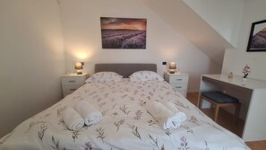 Ein Schlafzimmer mit einem Bett, zwei Nachttischen, einem Schreibtisch und einem Stuhl.