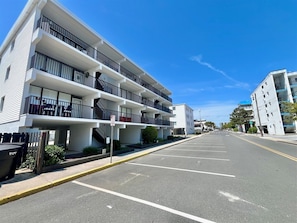 Un edificio a più piani con balconi, un parcheggio e un cielo azzurro limpido.