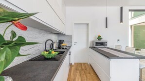 Eine moderne Küche mit schwarzer Arbeitsplatte, Edelstahlgeräten und Holzboden.