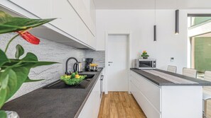 Eine moderne Küche mit schwarzer Arbeitsplatte, Edelstahlgeräten und Holzboden.