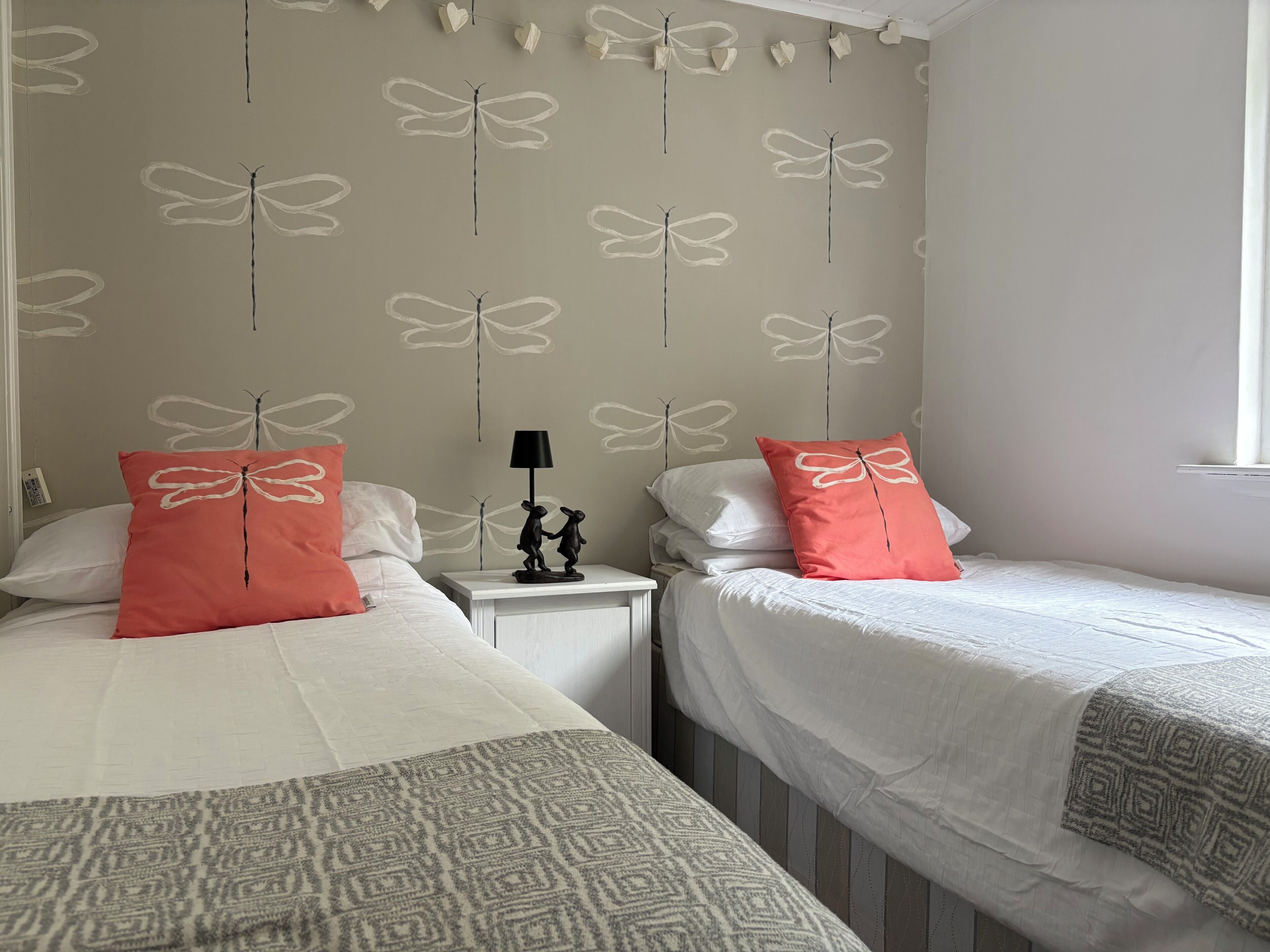 Une chambre avec deux lits, chacun recouvert d’une couverture à motifs, avec une literie blanche et des oreillers assortis.