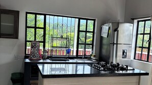 Una cocina con una isla grande, un refrigerador y una ventana con vista a follaje.