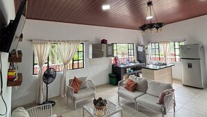 Un amplio espacio de sala con techo de madera, área de cocina y una mesa de comedor.