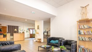 Un hall d’entrée spacieux, doté de canapés en cuir, d’une table basse, d’une bibliothèque et d’un comptoir d’accueil.