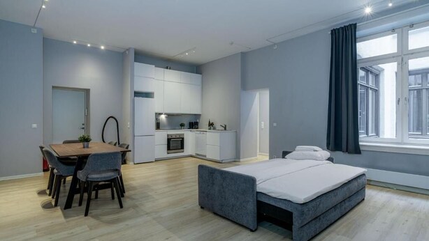 A modern apartment with a dining area, kitchenette, and a bed.