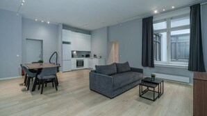 A modern apartment with a dining area, sofa, and kitchen.