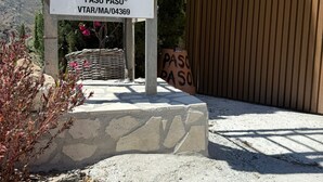 A sign for 'Vivienda Turística de Alojamiento Rural 'Paso Paso' VITAR/MAV/04369' with a logo, a wooden fence, and a mountainous background. - Boutique rural casita Paso Paso met adembenemend bergzicht en prachtig zwembad (Torrox)