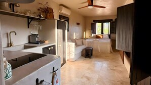 A modern kitchen with a central island, a dining area with a sofa, and a bedroom with a bed. - Boutique rural casita Paso Paso met adembenemend bergzicht en prachtig zwembad (Torrox)
