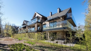 Ein modernes Mehrfamilienhaus mit großen Glasbalkonen, einer Ziegel-Fassade und einem geneigten Dach.