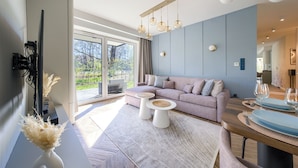 Ein modernes Wohnzimmer mit einer Couch, zwei Couchtischen und einem Essbereich mit Tisch für zwei Personen.