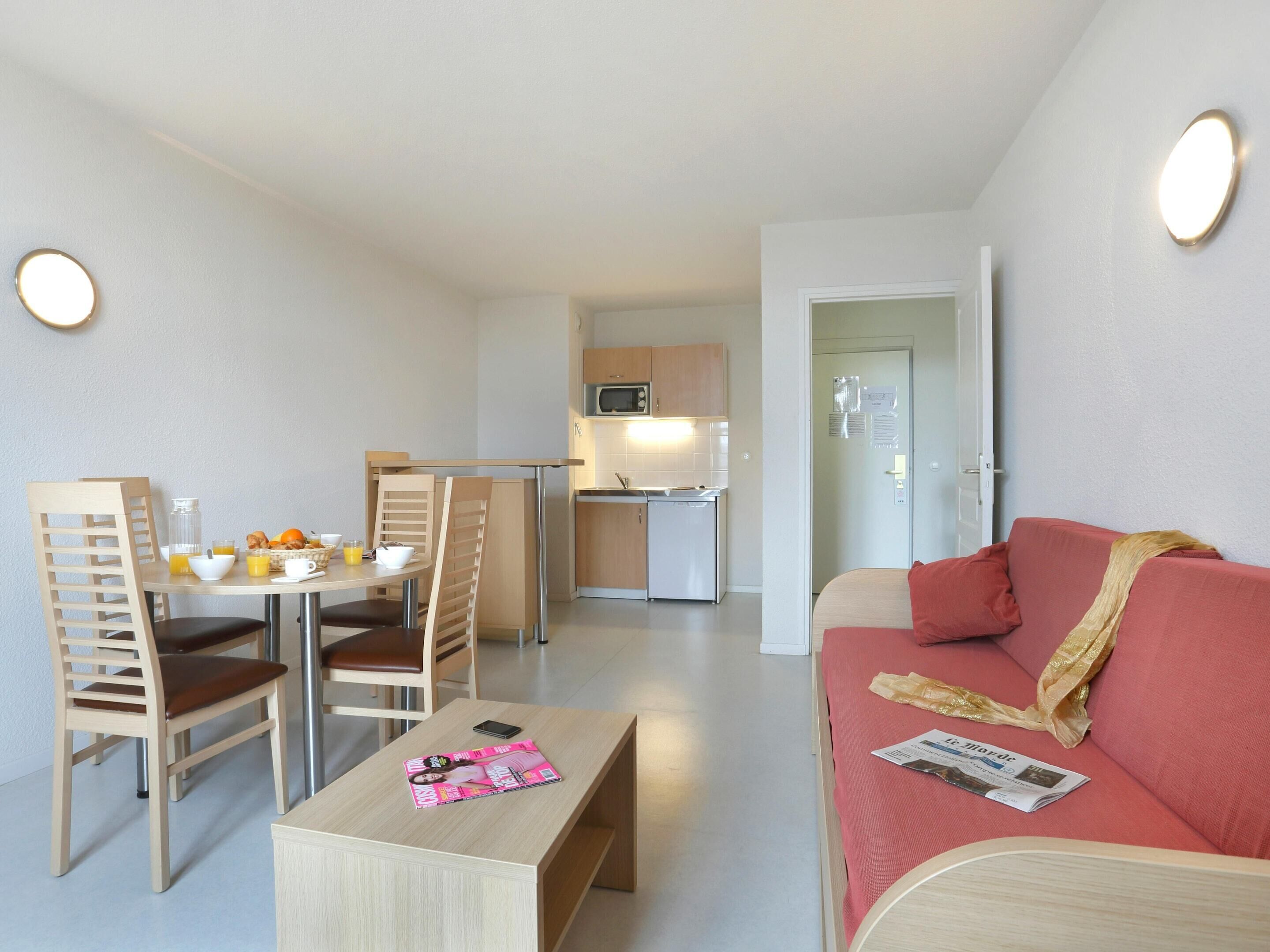 A compact living space with a dining area, kitchenette, and a sofa.