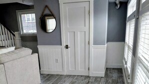 Een kamer met een grijze muur, een witte deur en een witte bank.