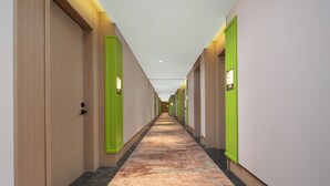 A long, narrow hotel corridor with doors on both sides, a carpeted floor, and recessed lighting. - Yiwu Aishang Mind Hotel (Jinhua)