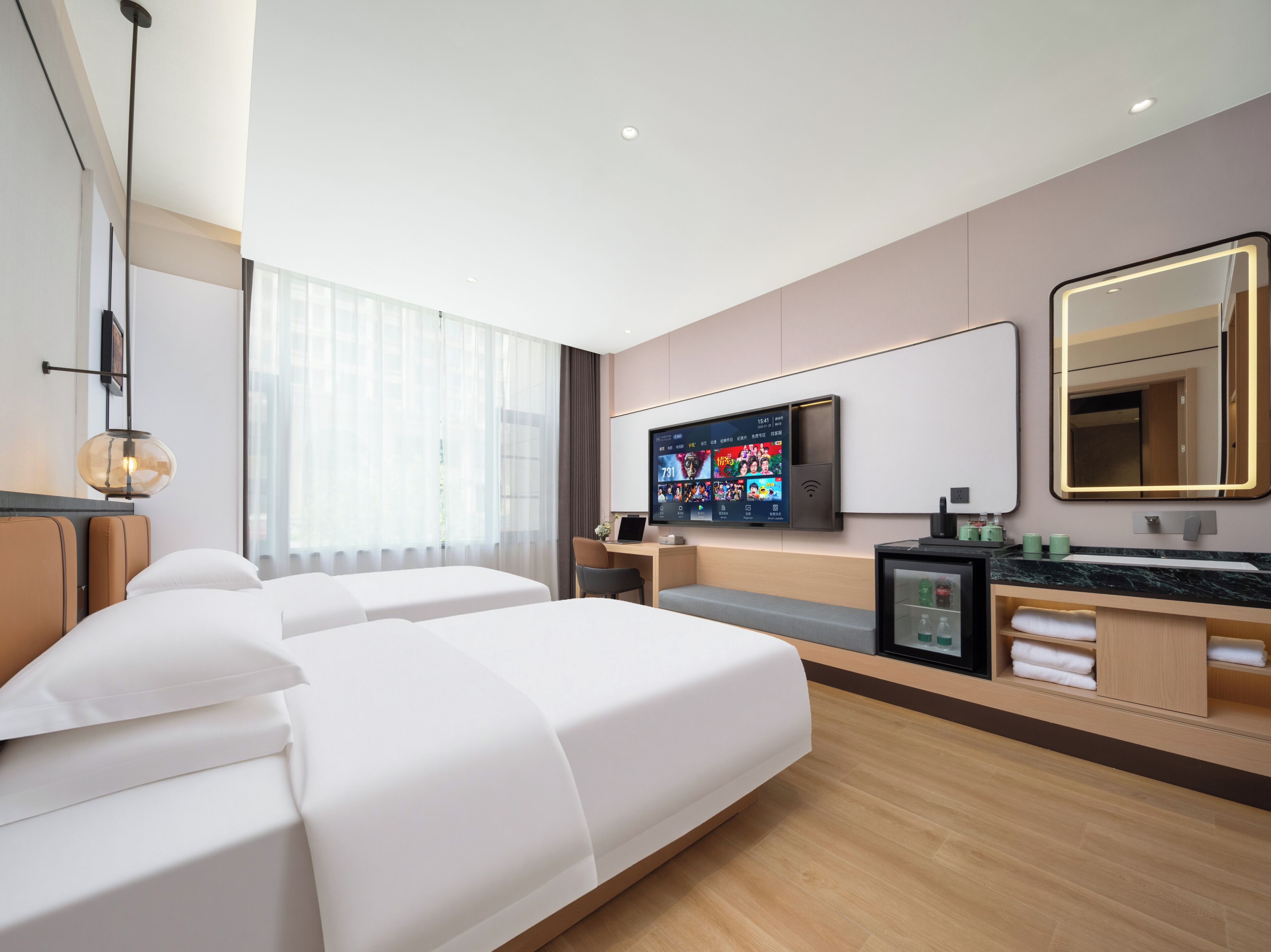 Hotelkamer met een bed, een bureau, een televisie en een badkamer met spiegel en wastafel.