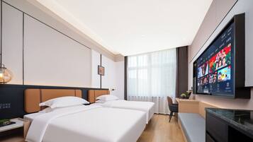 Habitación de hotel con dos camas, un escritorio, un televisor y un diseño moderno.