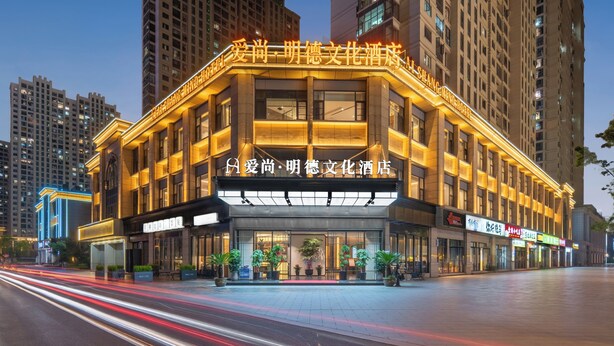 A hotel with a modern facade, large windows, and a prominent sign. - Yiwu Aishang Mind Hotel (Jinhua)
