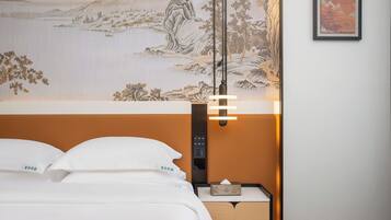 Habitación de hotel con cama, mesita de noche, lámpara de pared y un cuadro.