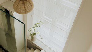 A staircase with a glass railing, a hanging light fixture, and a potted plant. - N46 Studio Apartment  (Warsaw)