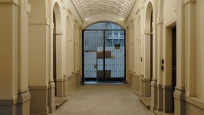 A corridor with ornate ceiling and columns, leading to a large arched doorway. - N46 Studio Apartment  (Warsaw)
