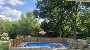 Ein Garten mit Schwimmbad, Holzzaun und Rasenfläche.