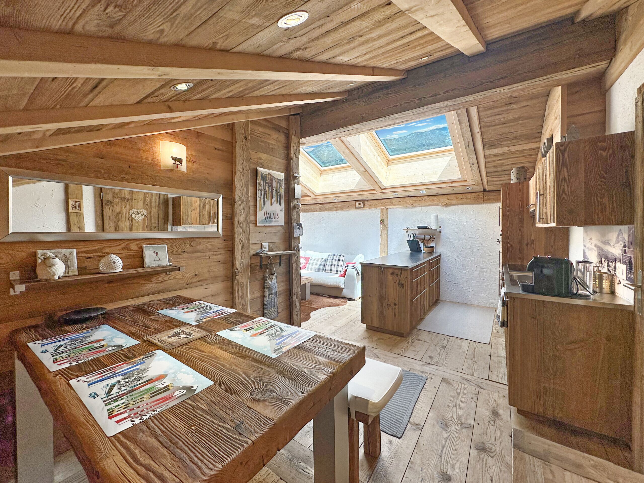 A wooden interior with a dining table, kitchen area, and skylights.