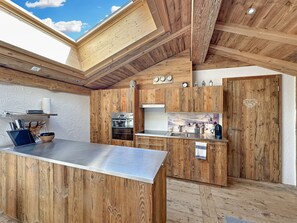 A modern kitchen with wooden cabinetry, a stainless steel countertop, and a skylight. - Matterhorn Alpine Hideaway - Cozy Renovated Apartm (Zermatt)